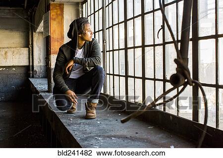 Androgynous Mixed Race woman crouching near window View Large Photo Image Stock Image - Androgynous Mixed Race woman crouching near window. Fotosearch