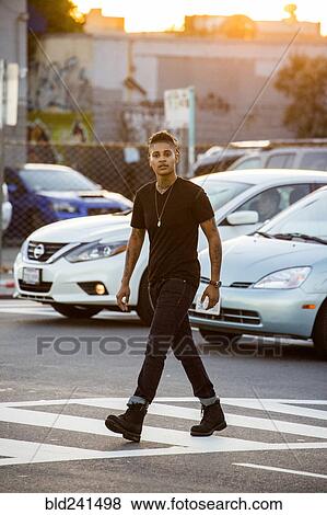 Stock Photo - Androgynous Mixed Race woman walking in urban crosswalk. Fotosearch