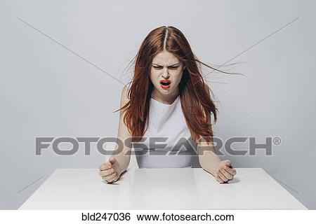 Angry Caucasian woman sitting at windy table View Large Photo Image Stock Photograph - Angry Caucasian woman sitting at windy table. Fotosearch