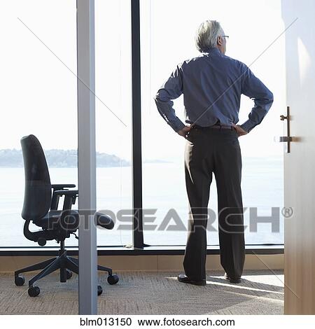 Stock Image - Asian businessman looking out office window. Fotosearch