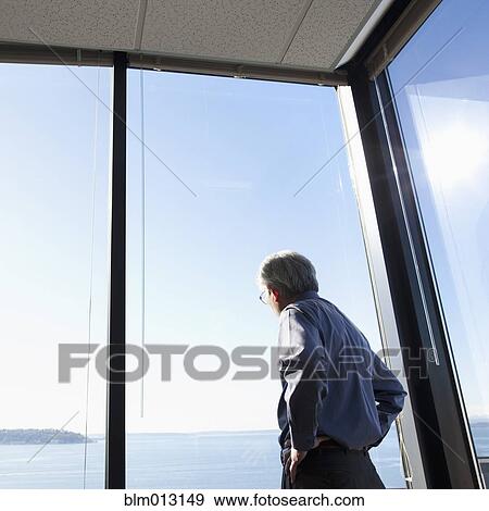 Stock Photo - Asian businessman looking out office window. Fotosearch