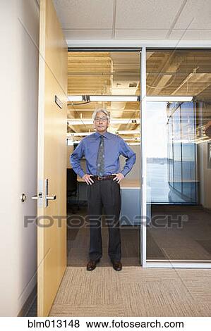 Stock Photo - Asian businessman standing in office doorway. Fotosearch
