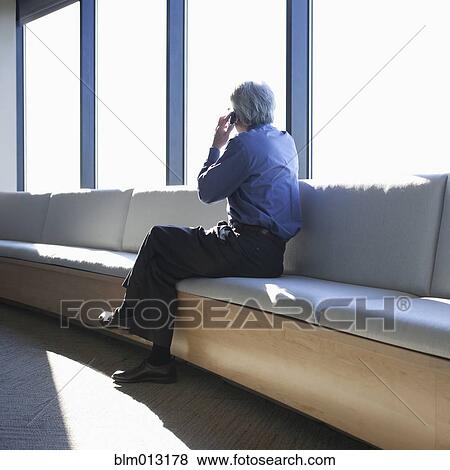 Stock Photo - Asian businessman talking on cell phone in lobby. Fotosearch