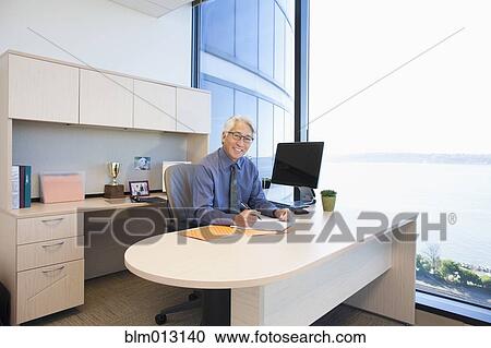 Stock Image - Asian businessman working at desk. Fotosearch