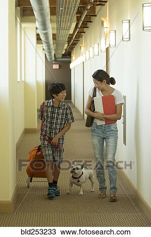 Stock Image - Asian mother and son in corridor with dog. Fotosearch