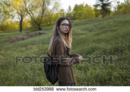 Stock Photo - Asian teenage girl carrying backpack in field. Fotosearch