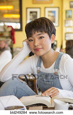 Asian teenage girl reading book in coffee shop View Large Photo Image Picture - Asian teenage girl reading book in coffee shop. Fotosearch