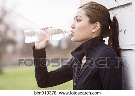 Stock Photo - Asian woman drinking bottle of water. Fotosearch