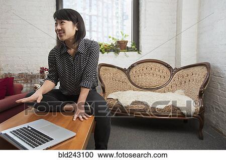 Stock Image - Asian woman gesturing near laptop. Fotosearch