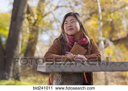 Asian woman holding journal at table in autumn View Large Photo Image Stock Image - Asian woman holding journal at table in autumn. Fotosearch