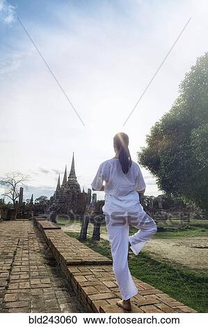 Stock Image - Asian woman practicing yoga near temple. Fotosearch