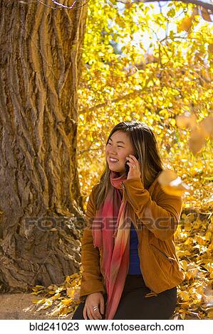Asian woman talking on cell phone in autumn View Large Photo Image Stock Image - Asian woman talking on cell phone in autumn. Fotosearch