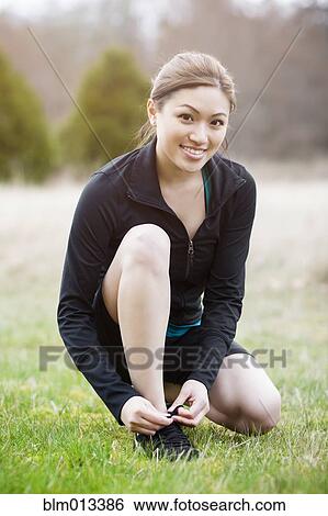 Asian woman tying her shoes View Large Photo Image Stock Photograph - Asian woman tying her shoes. Fotosearch