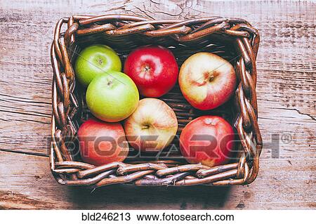 Stock Image - Basket of apples on wooden table. Fotosearch