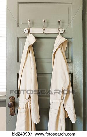 Stock Photo - Bathrobes hanging on hooks on door. Fotosearch