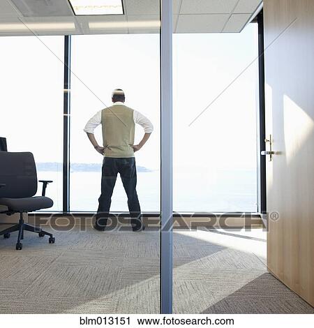 Stock Image - Black businessman looking out office window. Fotosearch