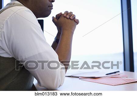 Stock Image - Black businessman sitting at desk. Fotosearch