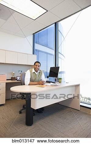 Black businessman sitting at desk View Large Photo Image Stock Photo - Black businessman sitting at desk. Fotosearch