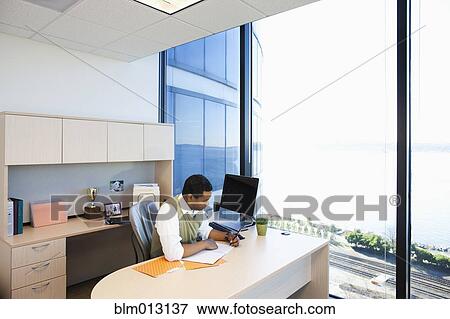 Stock Photo - Black businessman working at desk. Fotosearch