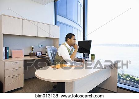 Stock Photo - Black businessman working at desk. Fotosearch