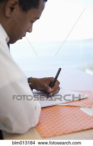 Picture - Black businessman writing in notebook. Fotosearch