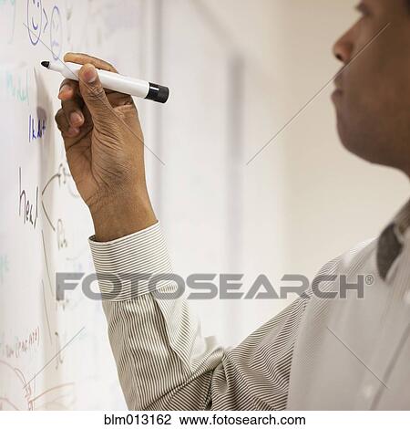 Stock Image - Black businessman writing on whiteboard. Fotosearch