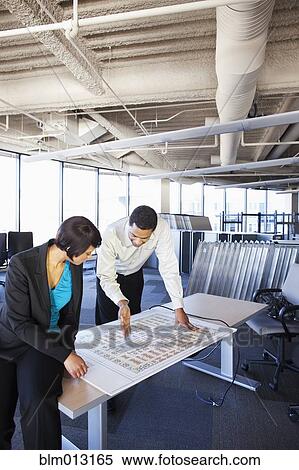 Stock Photography - Black businesspeople looking at office floor plans. Fotosearch