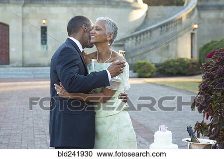 Stock Image - Black couple hugging near wedding cake. Fotosearch