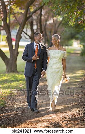 Stock Image - Black couple walking on path in park. Fotosearch