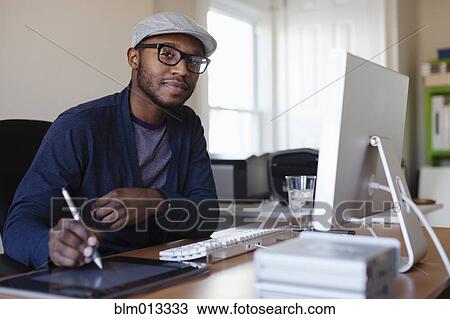 Stock Image - Black designer working at desk. Fotosearch