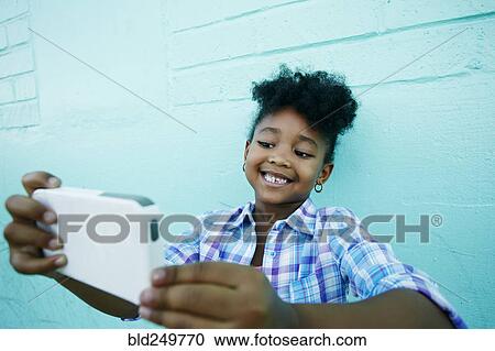 Stock Image - Black girl posing for cell phone selfie. Fotosearch