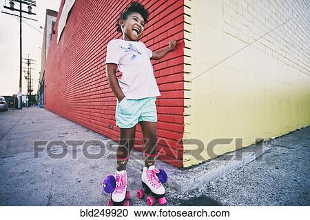Stock Image - Black girl wearing roller skates on urban sidewalk. Fotosearch