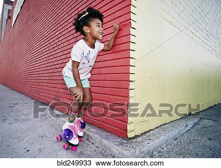 Stock Image - Black girl wearing roller skates peeking around corner. Fotosearch