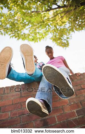 Black girls sitting on wall View Large Photo Image Stock Image - Black girls sitting on wall. Fotosearch