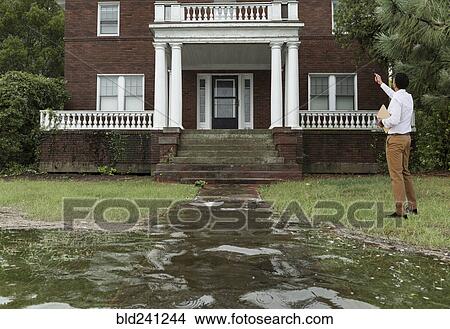 Black insurance adjuster examining flooding damage to house View Large Photo Image Picture - Black insurance adjuster examining flooding damage to house. Fotosearch