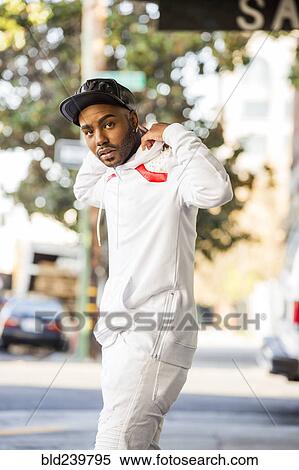 Stock Photography - Black man adjusting hoody in city. Fotosearch
