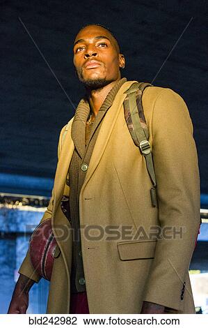 Stock Image - Black man wearing backpack holding basketball. Fotosearch