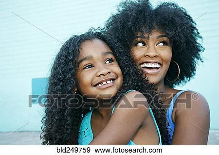 Stock Photo - Black mother and daughter looking away. Fotosearch