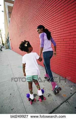 Black mother and daughter wearing roller skates holding hands View Large Photo Image Stock Photo - Black mother and daughter wearing roller skates holding hands. Fotosearch