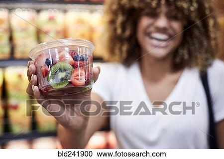 Stock Image - Black woman cup of fruit salad in grocery store. Fotosearch