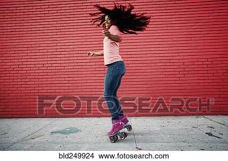 Picture - Black woman dancing on roller skates on sidewalk. Fotosearch