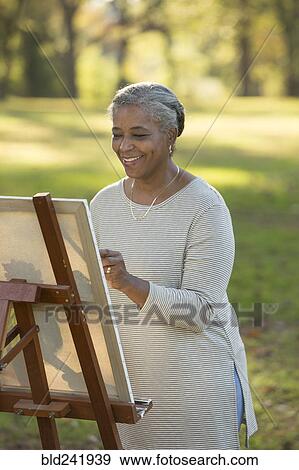 Black woman painting on canvas in park View Large Photo Image Stock Photo - Black woman painting on canvas in park. Fotosearch