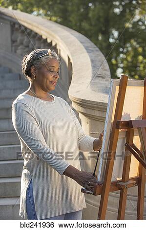 Black woman painting on canvas near stone staircase View Large Photo Image Stock Photograph - Black woman painting on canvas near stone staircase. Fotosearch