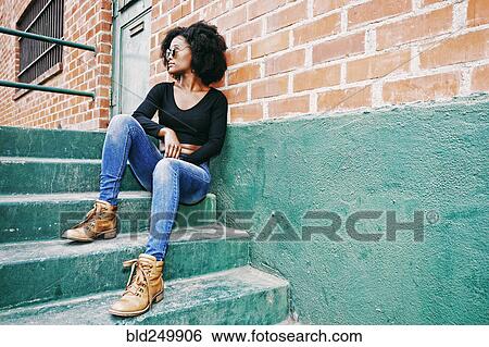 Stock Photograph - Black woman sitting on staircase outdoors. Fotosearch
