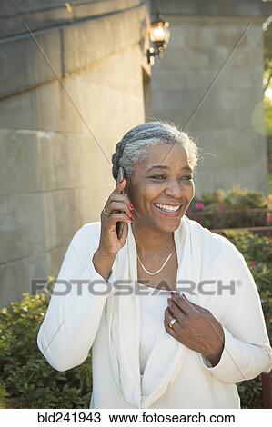Stock Image - Black woman talking on cell phone near stone staircase. Fotosearch