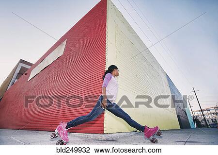 Stock Image - Black woman wearing roller skates gliding around corner. Fotosearch