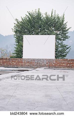 Blank board on brick wall near tree View Large Photo Image Picture - Blank board on brick wall near tree. Fotosearch