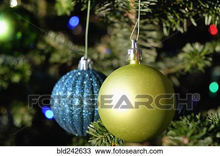 Stock Image - Blue and green ornaments hanging on Christmas tree. Fotosearch
