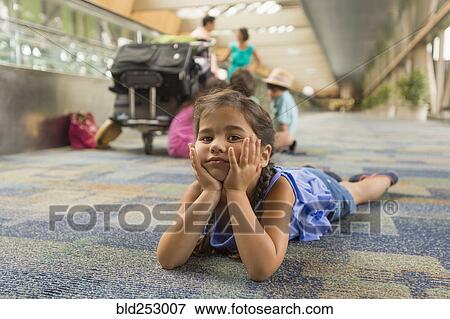 Stock Photo - Bored girl laying on floor of airport. Fotosearch