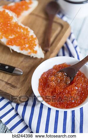 Stock Photo - Bowl of caviar near bread on cutting board. Fotosearch